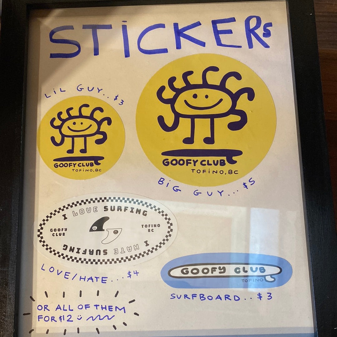 Sticker pack featuring various designs: 1. "Lil Guy" - Small circular yellow sticker with a smiling sun character and "Goofy Club Tofino, BC" text. 2. "Big Guy" - Larger circular yellow sticker with the same smiling sun character and "Goofy Club Tofino, BC" text. 3. "Love/Hate" - Oval sticker with a black and white design showing the text "Love Surfing" on one side and "Hate Surfing" on the other, with "Goofy Club Tofino, BC" text. 4. "Surfboard" - Oval blue and white sticker with "Goofy Club Tofino, BC"