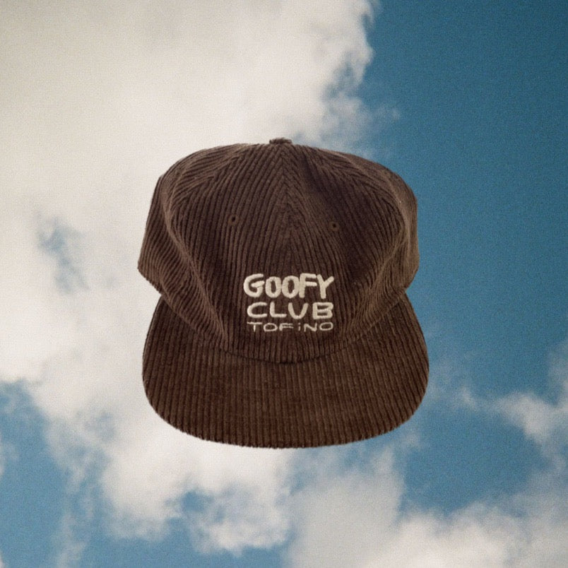 A brown corduroy textured baseball cap is pictured against a blue sky background. The words "GOOFY CLUB TOFINO" are embroidered on the front of the cap. 